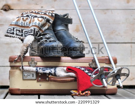 old ski boots on a small  suitcase full of warm clothes