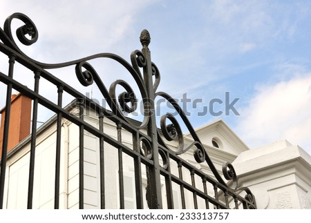 details of a black wrought iron gate in front of house
