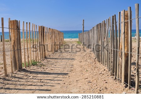 path in the sand leading to the sea bordered by wooden fence