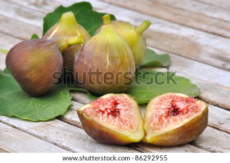 Half of figs and fig whole resting on a fig leaf
