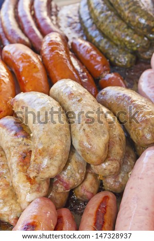 Assorted grilled types of sausages ready for sale at a farmer\'s market.