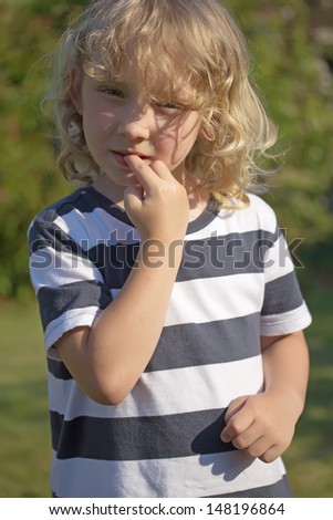 The blond boy in a striped shirt is biting his nails. Vertically.