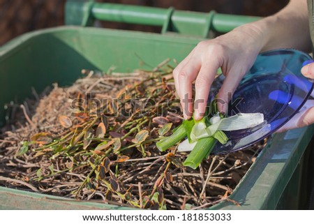Woman hand is sacking of organic waste into a green bins