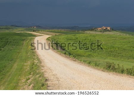 Dirty road in the middle of the Tuscan countryside. Storm dark sky in the background.