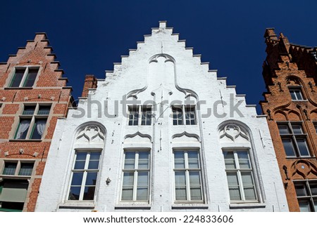 Historic houses in the center of Bruges (Belgium). Front view. White house between two red houses.