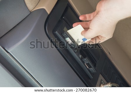 Truck driver is inserting tachograph card to the device inside the truck cab.