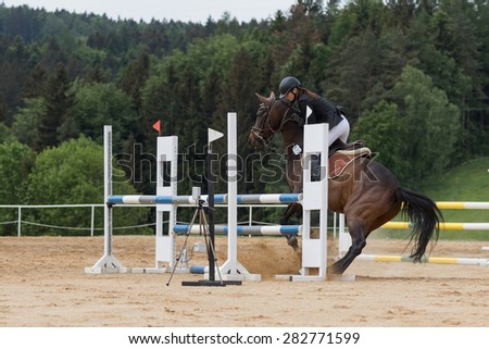 SVEBOHOV, CZECH REPUBLIC - MAY 23: Young horsewoman is mastering a brown horse who refused to jump an obstacle jumping at \