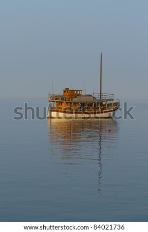 Cruise ship anchored in a calm sea, lit by the rising sun
