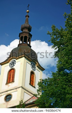 Village church tower with a clock tower. Blue sky with white clouds in the background. (Potstejn, Czech Republic)
