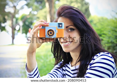 Smiling girl with vintage camera taking picture