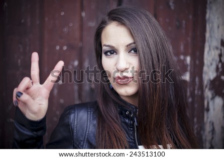 Beautiful girl in a victory pose on a wall background