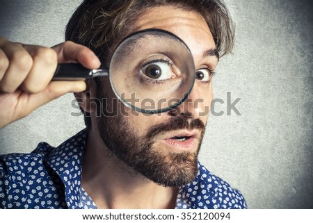 Astonished man looking through a magnifying glass