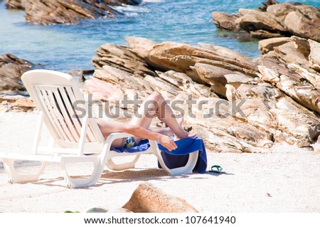 man sunbathing on beach bench