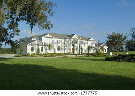 Massively large custom home or mansion with grand lawn and landscaping.