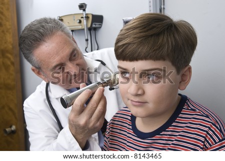 stock photo Mature hispanic physician examing young boy in doctor office