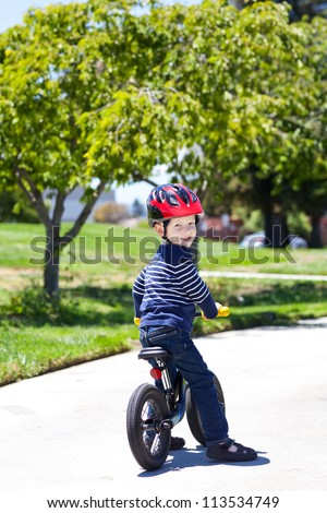 handsome toddler on a balance bike in a park