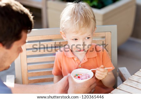 father and his son eating ice-cream in outdoor cafe