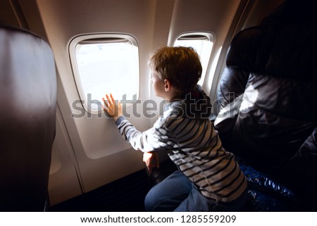little boy sitting in business class seat in plane waiting for vacation to start, travel and vacation concept
