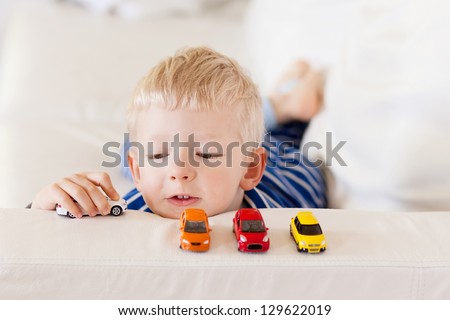 Young Caucasian Boy Plays With Colorful Toy Cars