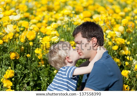adorable little boy and his father hugging and kissing in the park