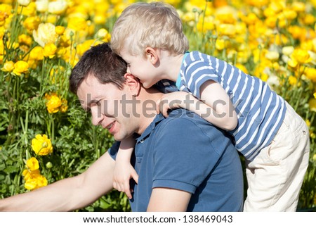 handsome young father and his son at the blooming flower field