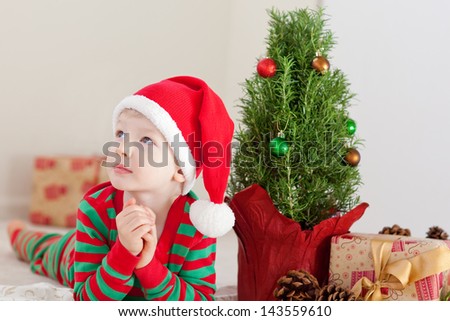 cute caucasian boy dreaming about presents at christmas time