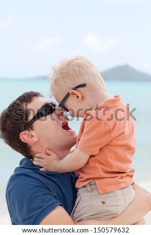 happy young man holding his cute toddler son tight and having fun together