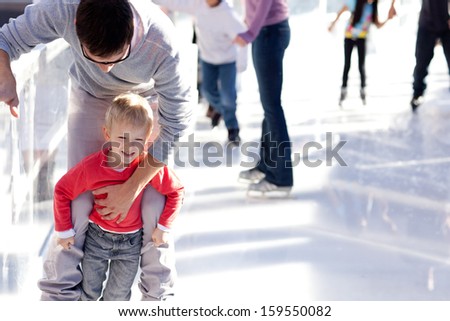 Young Father Teaching His Little Smiling Son Ice Skating And Having Fun Time