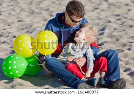 happy cheerful family of two spending fun time with balloons at the beach