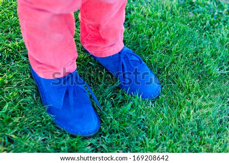closeup of kids feet in beautiful blue suede shoes on grass