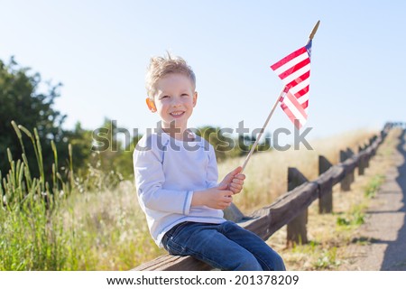 little boy holding american flag and celebrating 4th of July