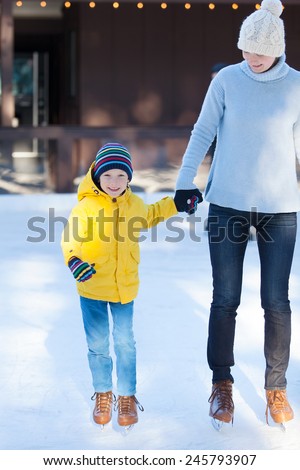 happy family of mother and her son enjoying ice skating together at winter at outdoor skating rink