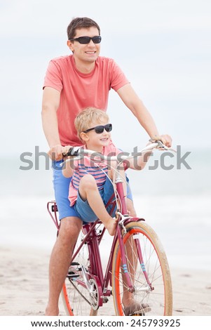happy family of father and son enjoying their time together while biking at the beach