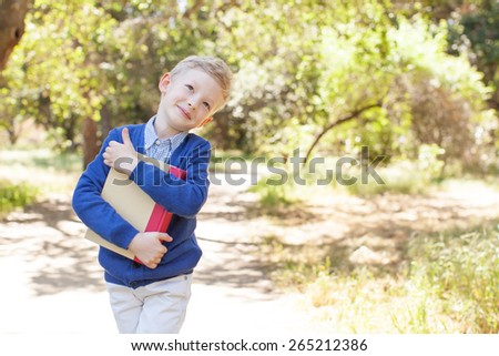 smiling little schoolboy holding book ready to go to school, back to school concept