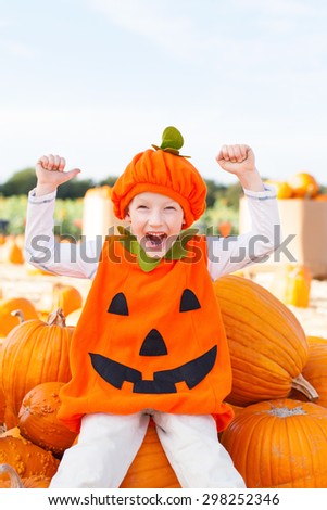 smiling little boy in pumpkin costume having fun at pumpkin patch, american tradition
