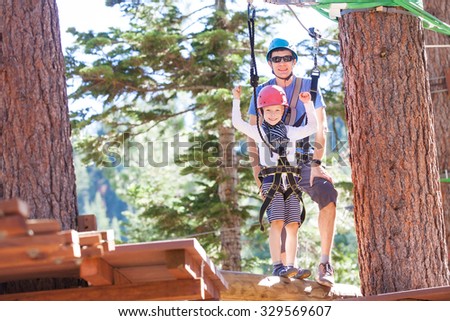 positive little boy and his father climbing at outdoor treetop adventure park being active and healthy together