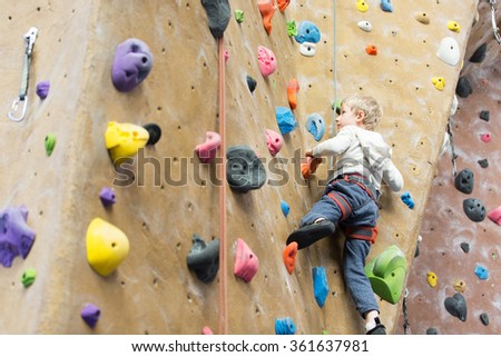little active boy rock climbing at indoor gym