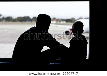 silhouettes of father and son watching the plane