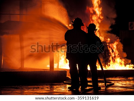 Firemen using water hose on fire