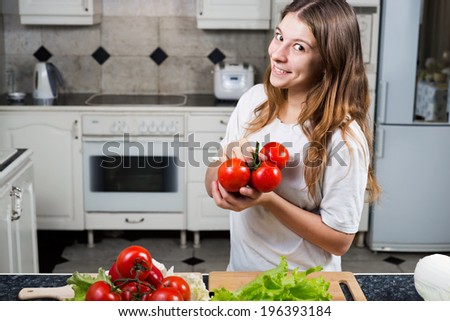 Young woman with tomato showing bunch of tomatoes for fresh salad.