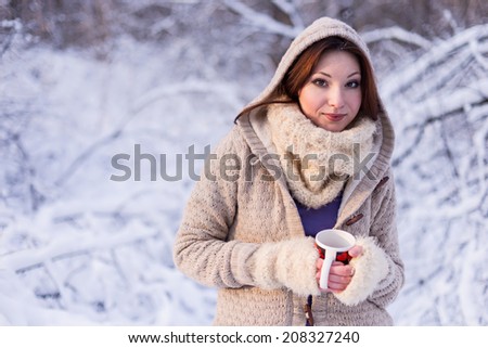 Winter woman in snow looking  at camera outside on snowing cold winter day.