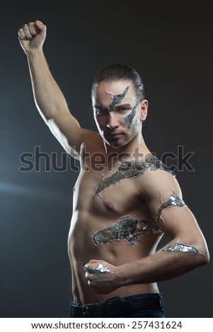 Young handsome man with  mosaic body art, standing in front of black background: body-art project