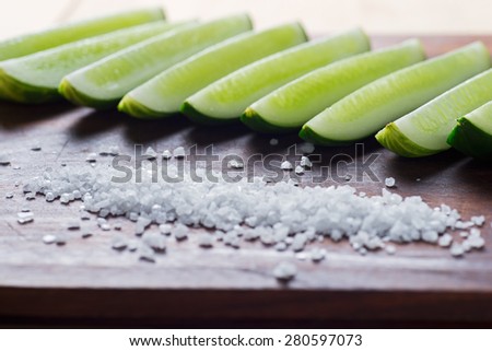 The cut cucumber on a board with sea salt.