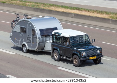 FRANKFURT, GERMANY - JULY 21: Land Rover Defender with a small caravan travelling at the A5 highway in Germany. July 21, 2015 in Frankfurt Main, Germany