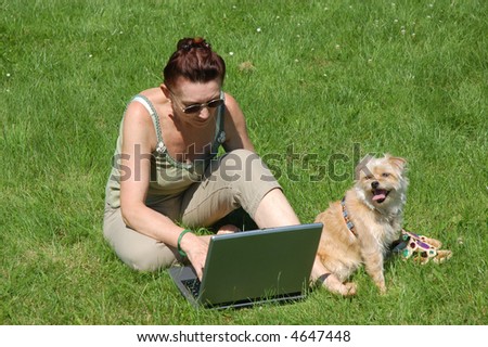 Senior woman with laptop and dog in a park