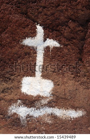 Painted cross on the red rock in Santorini, Greece