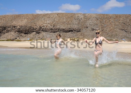 stock photo : Two young women running on the beach, Fuerteventura, Spain