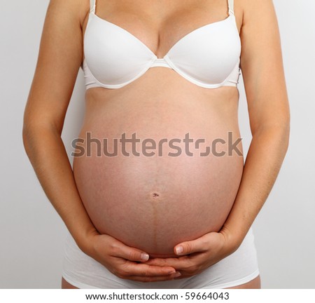 stock photo Young pregnant woman in white underwear holding her belly