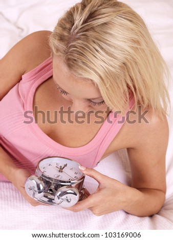Young Woman In Bed Setting Alarm Clock