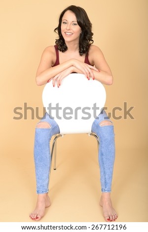 Happy Smiling Attractive Young Woman Sitting in a Chair Looking At The Camera
